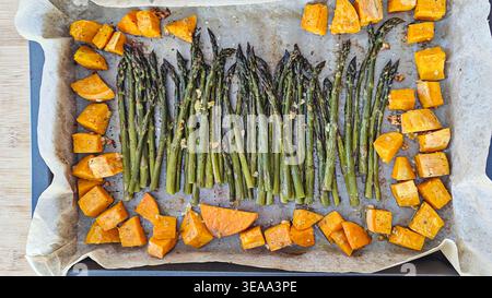 Gerösteter Spargel und Süßkartoffelwürfel auf dem Backblech mit Blick von oben Stockfoto