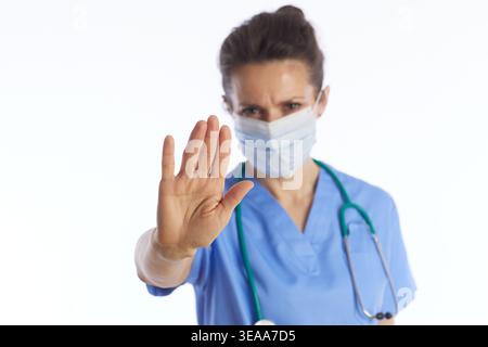 Nahaufnahme einer Ärztin in Peelings und Maske machen ein Stoppschild mit ihrer Hand, um Sicherheitsprotokolle und Viruspräventionsmea zu kommunizieren Stockfoto