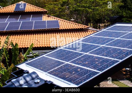 Photovoltaik-Solarpaneele, die auf dem Dach eines rustikalen Hauses mit Tonziegeln installiert sind, und eine solarbetriebene Straßenleuchte im Vordergrund, die Nachhaltigkeit unterstreicht Stockfoto