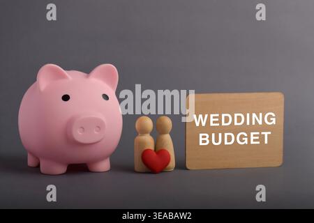 Schweinebank mit zwei Figuren, rotem Herz und Schild „Wedding Budget“. Das Konzept, Geld für Heirat, Finanzplanung und beziehungsgoa zu sparen Stockfoto