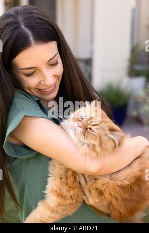 Lächelnde Frau, die draußen süße Ingwerkatze hält Stockfoto