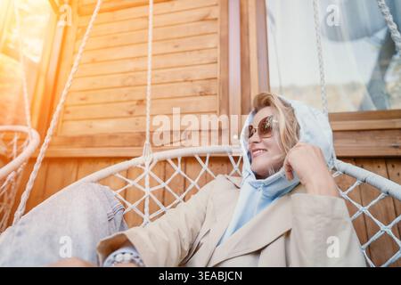 Frau, die sich in einem Hängestuhl auf einer hölzernen Veranda entspannt Stockfoto