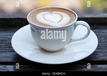 Blick von oben auf heißen Kaffee in weiß strukturierter Keramikbecher auf altem, verwittertem Holzhintergrund. Minimalistische Komposition mit großem Kopierraum. Stockfoto