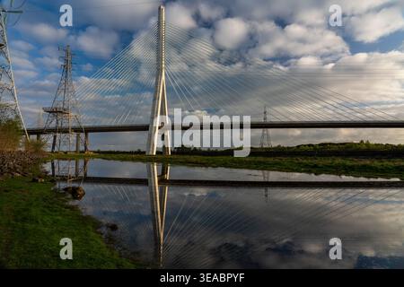 Flintshire Bridge mit Kabelstegen und Stabseilen, die in Gezeitenwasser neben Strommasten unter blauem Himmel reflektiert werden Stockfoto