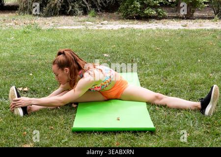Der Personal Trainer hilft beim Stretching im Freien und betont die richtige Haltung und Bewegung Stockfoto