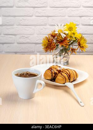 Tasse schwarzen Kaffee, frische Croissants auf dem weißen Porzellanteller. Stockfoto