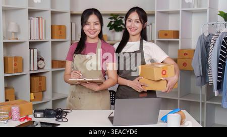 Glückliche asiatische Frauen, Kleinunternehmer mit Boxen im Home Office Stockfoto