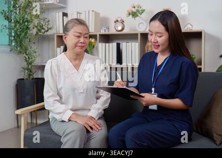 Asiatische Krankenschwester berät Seniorin während des häuslichen Gesundheitsbesuchs Stockfoto
