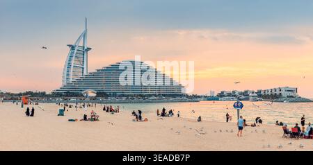 10. Januar 2026, Dubai, VAE: Menschen genießen Freizeit am Jumeirah Beach mit der ikonischen Architektur von Burj Al Arab und Jumeirah bei Sonnenuntergang Stockfoto