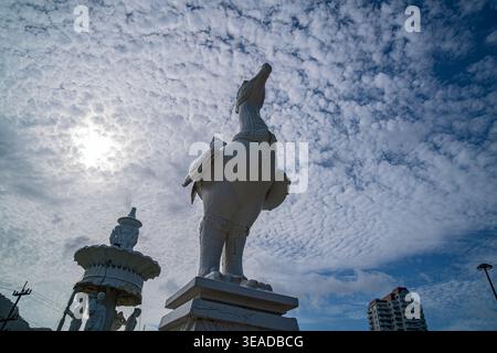 Phuket Thailand. 13. August 2025: Eine markante weiße Skulptur steht hoch unter einem strukturierten, bewölkten Himmel, deren anmutige Form sich mit dem flauschigen c kontrastiert Stockfoto
