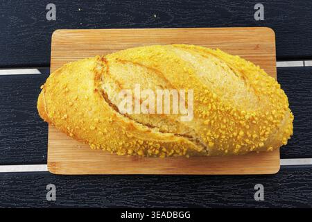Blick von oben auf einen kroatischen Maisbrotlaib, der auf einem Holzschneidebrett auf einem dunklen Lattentisch steht. Selektiver Fokus Stockfoto