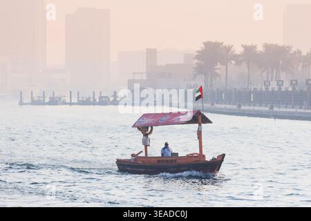 12. Januar 2026, Dubai, VAE: Traditionelle Abra-Boote transportieren Passagiere über den Dubai Creek und verbinden alte und neue Teile der Stadt mit einem trüben Skyl Stockfoto