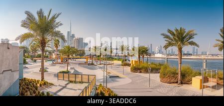 12. Januar 2026, Dubai, VAE: Palmen, die einen urbanen Skatepark entlang der Uferpromenade umrahmen und die moderne Skyline und den Burj Khalifa zeigen Stockfoto