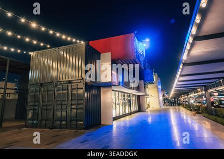 11. Januar 2026, Dubai, VAE: Urbane Architektur, die bunte Schiffscontainer stapelt und zu Einzelhandelsgeschäften und Restaurants in einer lebhaften Nachtstadt macht Stockfoto