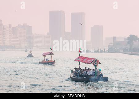 12. Januar 2026, Dubai, VAE: Traditionelle Abra-Boote transportieren Passagiere über den Dubai Creek und verbinden alte und neue Teile der Stadt mit einem trüben Skyl Stockfoto