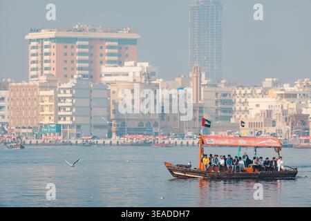 12. Januar 2026, Dubai, VAE: Traditionelles Abra-Boot, das den Creek überquert und Passagiere mit der Skyline der Stadt im Hintergrund bewegt Stockfoto