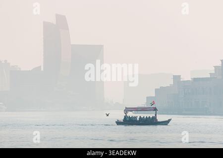 12. Januar 2026, Dubai, Vereinigte Arabische Emirate: Abra-Boot transportiert Passagiere über den Creek, wobei die Skyline der Stadt und die traditionelle Architektur durch den Heav erscheinen Stockfoto