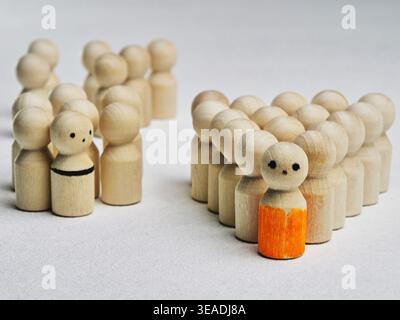 Die Holzfiguren sind angeordnet, um Führungsqualitäten und Teamarbeit zu demonstrieren, wobei eine Figur in Orange hervorhebt. Andere Figuren bilden Gruppen auf einem neutralen Backgro Stockfoto