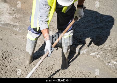 Bauarbeiter eine Betonplatte an einem sonnigen Tag nivellieren das Konzept der harten Arbeit Stockfoto