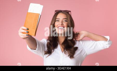 Begeisterte Reisende, die Reisedokumente in einem hellen Studio-Setting halten Stockfoto