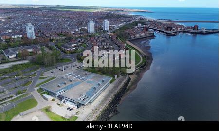 Das Foto zeigt das National Glass Centre am Ufer des Flusses Wear in Sunderland. In der Ferne sind Roker und seine Küste sichtbar. Die Region verfügt über verschiedene Gebäude und einen klaren Blick auf den Fluss. Die Szene nimmt einen wichtigen Ort in der Stadt Sunderland ein und betont die Verbindung zwischen dem Wasser und der nahe gelegenen Stadtentwicklung. Stockfoto
