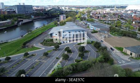 Die Szene zeigt den Sunderland St Peters Campus in Tyne and Wear, der sich in der Nähe des Ufers des Flusses befindet. Verschiedene Gebäude sind zu sehen, darunter moderne Architektur und nahe gelegene Wohngebiete. Das Bild zeigt leere Parkplätze und Straßen, was auf einen ruhigen Tag auf dem Campus hinweist. Im Hintergrund befinden sich zusätzliche Gebäude und Grünanlagen entlang des Flusses, die eine Momentaufnahme der Gegend ermöglichen. Stockfoto
