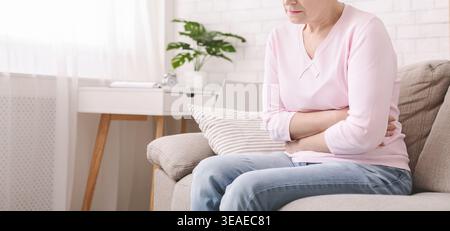Unglückliche Seniorin, die zu Hause unter Bauchschmerzen leidet Stockfoto