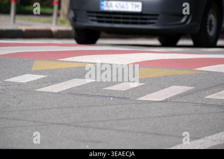 Leuchtend rote und gelbe Linien signalisieren Autos, dass sie langsamer werden, wenn sie sich einem Quersteg nähern. Stockfoto
