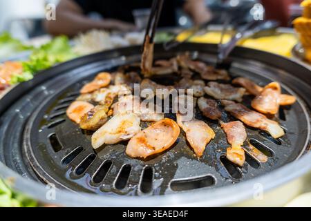 Kochende koreanische BBQ Schweinebauchkoche auf traditionellem Grill mit Essstäbchen, Nahaufnahme von Stockfoto
