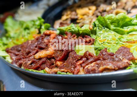 Mariniertes koreanisches Rindfleisch Bulgogi serviert auf Salatblättern mit Hochglanzsauce, Nahaufnahme von Lebensmitteln Stockfoto