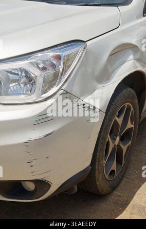 Defekter Stoßfänger und Kotflügel des weißen Autos, Dellen und schwarze Abriebspuren an Karosserie, Autounfallversicherung oder Fahrzeugreparaturkonzept im Soft Focus Stockfoto
