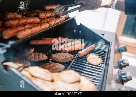 Grillfest. Kochen auf Holzkohlegrill. Saftige gegrillte Würstchen und Burger bei Sommerversammlungen Stockfoto
