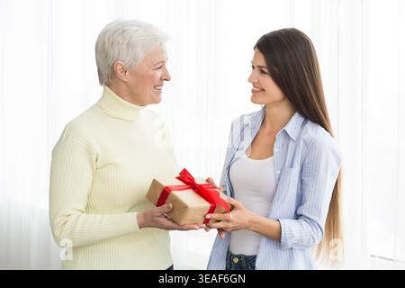 Eine ältere Frau erhält ein Geschenk von einer erwachsenen Tochter Stockfoto