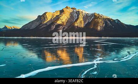 Frozen Lake und schneebedeckte Berge reflektieren bei Sonnenaufgang im Winter Stockfoto