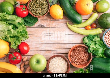 Vielfalt von frischem Gemüse, Obst und Samen um Holztisch mit Kopierraum in der Mitte angeordnet, natürliche Kochhintergrund und gesund Stockfoto