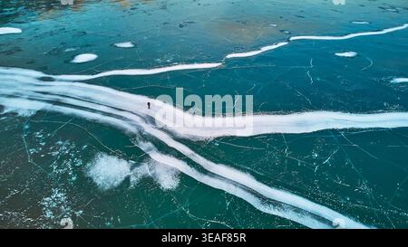 Eismuster aus dem gefrorenen Abraham Lake mit Hiker in Alberta Winter Stockfoto