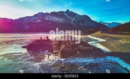 Der Rocky Aufschluss des Lake und die schneebedeckten Berge im Wintersonnenlicht Stockfoto