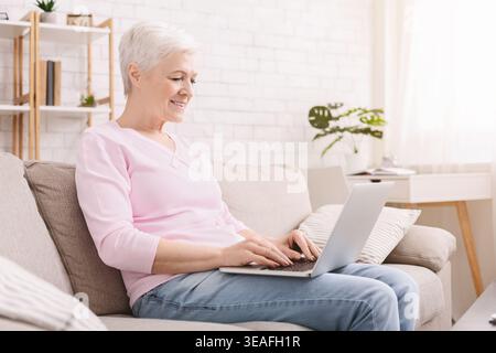 Reife Frau, die auf ihrem Laptop schreibt Stockfoto