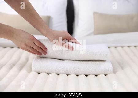 Frau, die Handtücher aus dem Bett nimmt, Nahaufnahme Stockfoto
