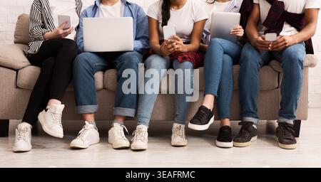Gruppe von Freunden, die sich mit digitalen Aktivitäten auf einer Couch in einem modernen Wohnzimmer beschäftigt Stockfoto