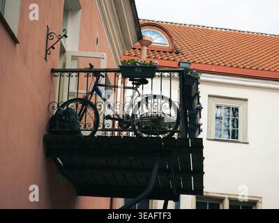 Fahrrad auf schmiedeeisernem Balkon mit Blumenkästen in einem rosafarbenen Gebäude in der Altstadt von Tallinn, Estland, im Frühling Stockfoto