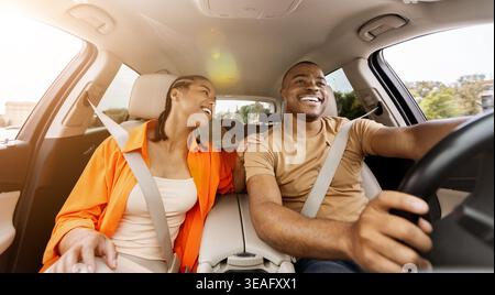 Das junge afroamerikanische Paar fährt gern zusammen und lächelt im Auto Stockfoto