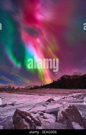 Nordlichter über dem gefrorenen See mit Winterfelsen und schneebedeckten Landschaften Stockfoto