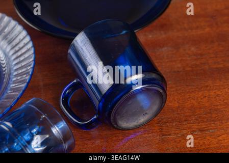 Stillleben mit blauen Glaswaren auf Holz. Dunkle, stimmungsvolle Beleuchtung unterstreicht Glasstrukturen und satte Farben. Relevant für Speisen, Barware oder vin Stockfoto