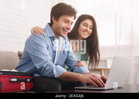Glückliches Paar, das Reisen plant, Tickets online auf dem Laptop Bucht Stockfoto