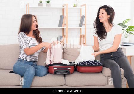 Freunde, die ihr Gepäck vor ihrer Reise auf einer gemütlichen Couch für die Heimreise vorbereiten Stockfoto