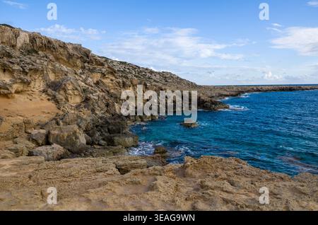 Felsige Küstenklippe mit blauem Meer unter klarem Himmel Stockfoto