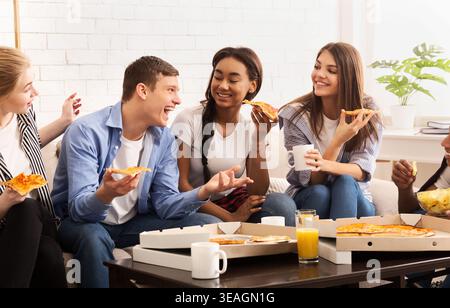 Freunde genießen gemeinsam Pizza in gemütlicher Innenumgebung am Abend Stockfoto