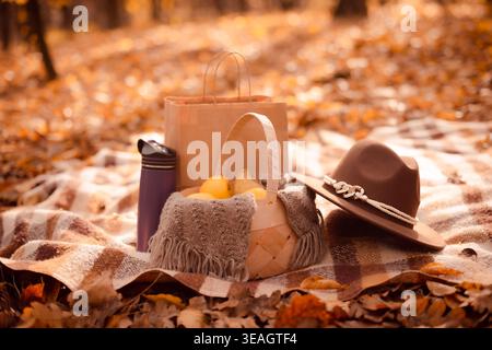 Herbststillleben mit wiederverwendbarer Flasche und Früchten auf dem Hintergrund goldener Blätter Stockfoto