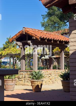 Die ursprünglichen Kirchenglocken aus dem Jahr 1818 hängen von der mit Fliesen überdachten Plattform im Garten der Mission San Luis Obispo – San Luis Obispo, Kalifornien, Oktober 2025 Stockfoto